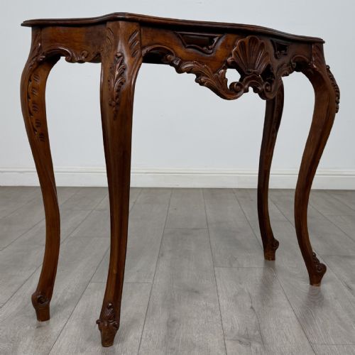 fig 7. A carved mahogany French style side table featuring exaggerated cabriole legs, a shell motif apron, and a serpentine tabletop.