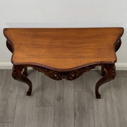 fig 8. A carved mahogany French style side table featuring exaggerated cabriole legs, a shell motif apron, and a serpentine tabletop.