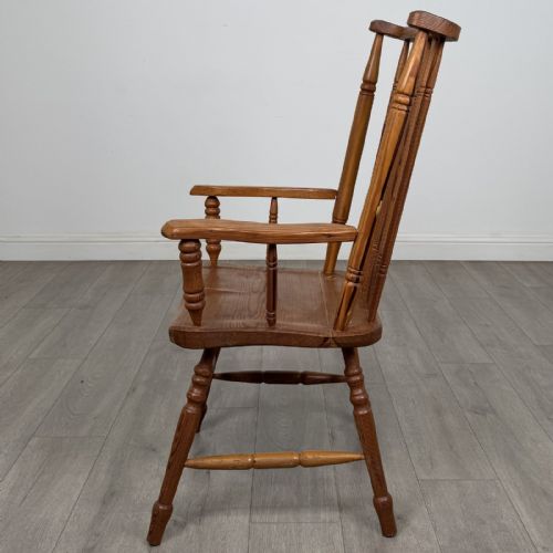 fig 1. A pitch pine stick back armchair featuring vertical spindle uprights, turned legs, shaped armrests, and turned stretchers.