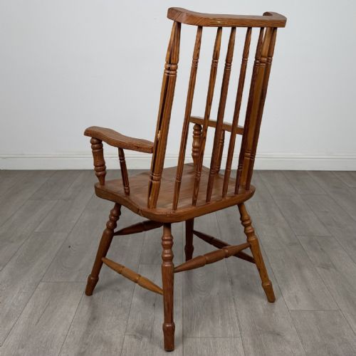 fig 2. A pitch pine stick back armchair featuring vertical spindle uprights, turned legs, shaped armrests, and turned stretchers.