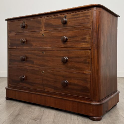fig 1. An antique Victorian mahogany chest of drawers featuring two short drawers above three long graduated drawers with turned knobs and bun feet.