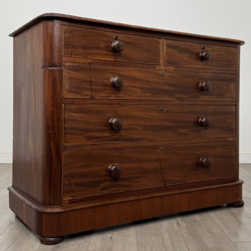 fig 7. An antique Victorian mahogany chest of drawers featuring two short drawers above three long graduated drawers with turned knobs and bun feet.