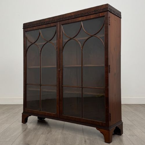 fig 1. An Edwardian dark mahogany display cabinet featuring twin astragal glazed doors with Gothic tracery and bracket feet.
