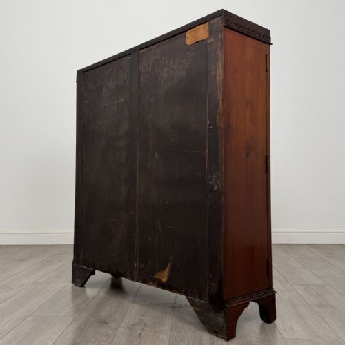 fig 5. An Edwardian dark mahogany display cabinet featuring twin astragal glazed doors with Gothic tracery and bracket feet.