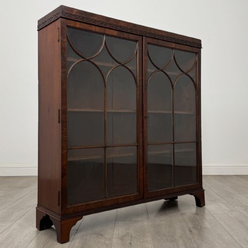 fig 7. An Edwardian dark mahogany display cabinet featuring twin astragal glazed doors with Gothic tracery and bracket feet.