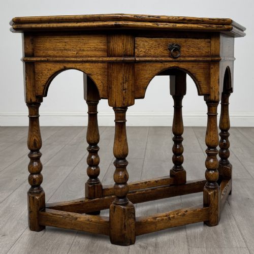 fig 6. An early 20th-century golden oak fold-over tea table featuring an octagonal top, arched frieze with a single central drawer, turned legs, and lower stretchers.
