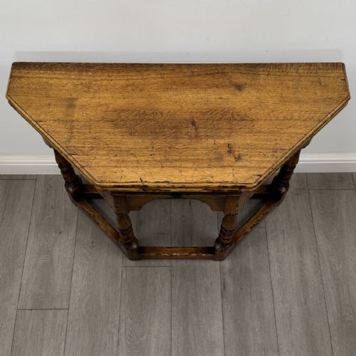 fig 7. An early 20th-century golden oak fold-over tea table featuring an octagonal top, arched frieze with a single central drawer, turned legs, and lower stretchers.