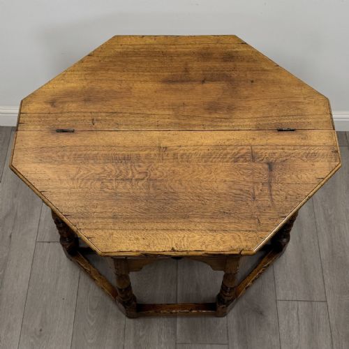 fig 8. An early 20th-century golden oak fold-over tea table featuring an octagonal top, arched frieze with a single central drawer, turned legs, and lower stretchers.