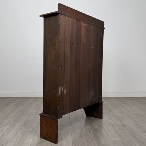 fig 3. An antique dark oak open bookcase featuring four horizontal shelves, a low raised top gallery, and shaped bracket feet.
