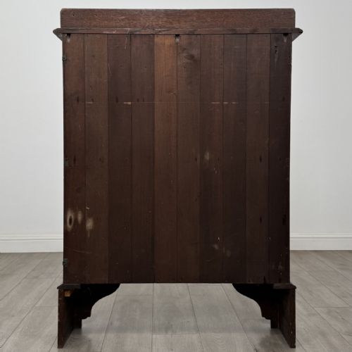 fig 4. An antique dark oak open bookcase featuring four horizontal shelves, a low raised top gallery, and shaped bracket feet.