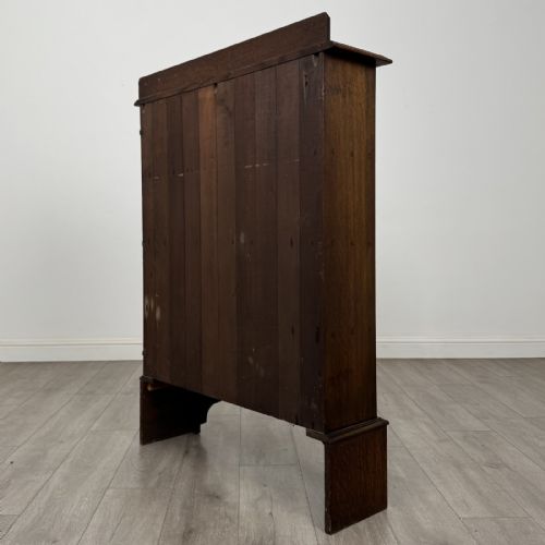 fig 5. An antique dark oak open bookcase featuring four horizontal shelves, a low raised top gallery, and shaped bracket feet.