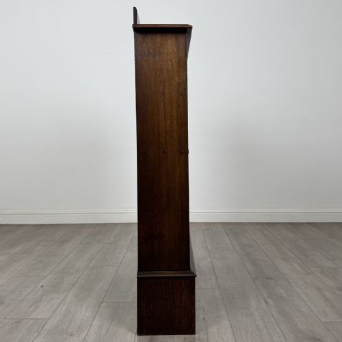 fig 6. An antique dark oak open bookcase featuring four horizontal shelves, a low raised top gallery, and shaped bracket feet.