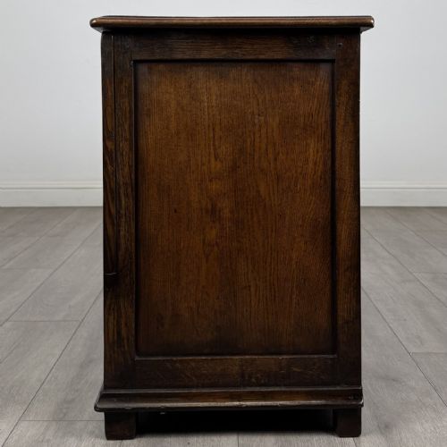 fig 2. A dark oak Georgian style drop-front mule chest featuring three arched fielded panels and two lower drawers with brass swan-neck handles.