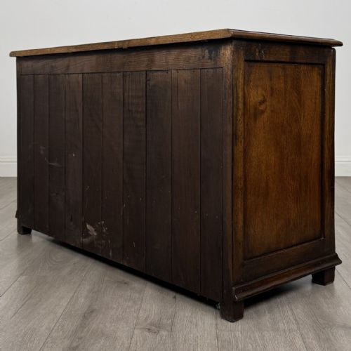fig 5. A dark oak Georgian style drop-front mule chest featuring three arched fielded panels and two lower drawers with brass swan-neck handles.