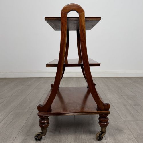 fig 1. A three-tier antique mahogany open bookcase featuring arched reeded uprights, turned legs, and brass castors.
