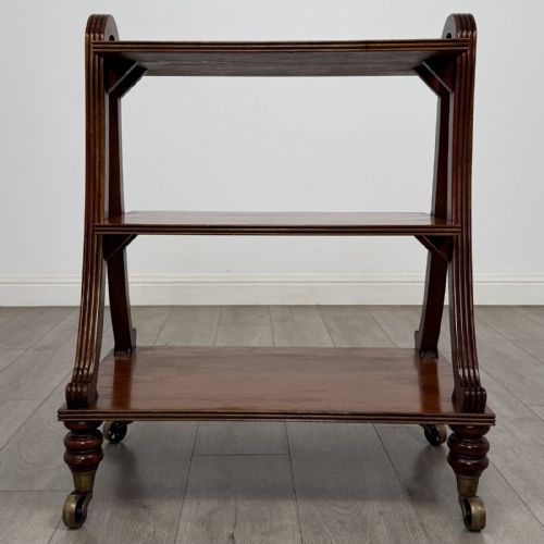 fig 3. A three-tier antique mahogany open bookcase featuring arched reeded uprights, turned legs, and brass castors.