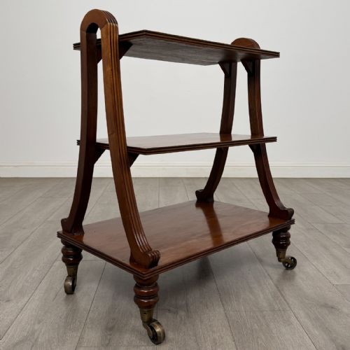 fig 6. A three-tier antique mahogany open bookcase featuring arched reeded uprights, turned legs, and brass castors.