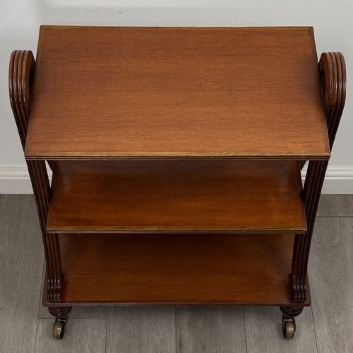 fig 7. A three-tier antique mahogany open bookcase featuring arched reeded uprights, turned legs, and brass castors.