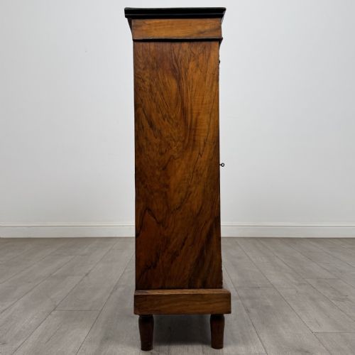 fig 7. A 19th-century Victorian walnut pier cabinet featuring floral marquetry inlays, decorative gilt metal mounts, a single glazed glass door, and velvet-lined interior shelves.
