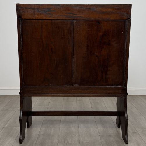 fig 4. A dark carved oak high-back settle featuring a floral carved frieze across the top and shaped side armrests.