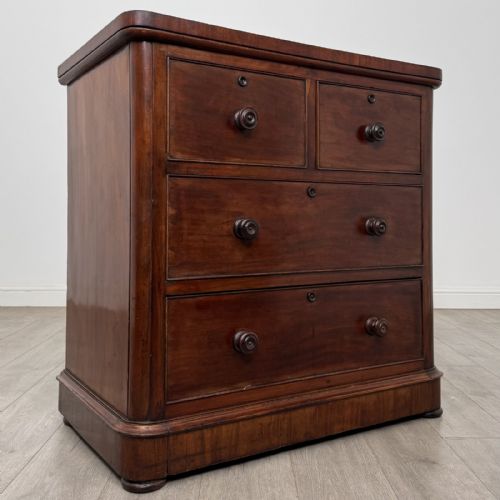 fig 7. An antique Victorian mahogany chest of drawers featuring two short drawers over two long drawers with turned wooden handles and a plinth base.