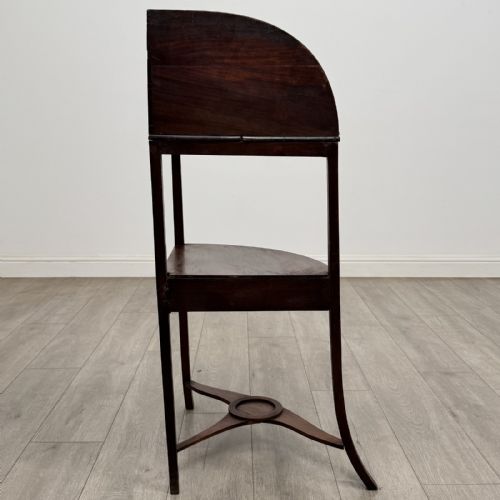 fig 4. A Georgian style mahogany corner washstand with a high curved splashback gallery, central drawer tier with brass rosette handles, and splayed legs joined by a circular lower stretcher.