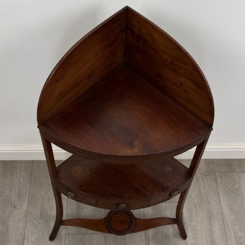 fig 6. A Georgian style mahogany corner washstand with a high curved splashback gallery, central drawer tier with brass rosette handles, and splayed legs joined by a circular lower stretcher.