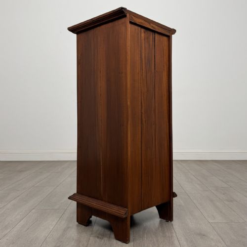 fig 3. A tall and narrow warm brown mahogany chest of drawers with seven stacked drawers and brass drop handles.