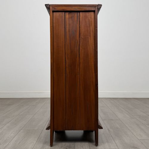 fig 4. A tall and narrow warm brown mahogany chest of drawers with seven stacked drawers and brass drop handles.