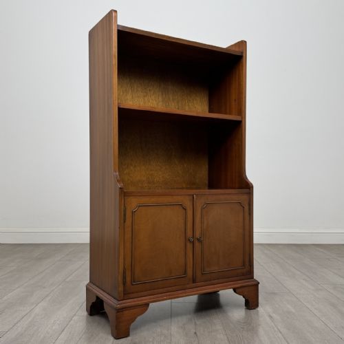 fig 1. A mahogany open bookcase featuring two upper shelves with shaped side galleries above a two-door lower cupboard on bracket feet.