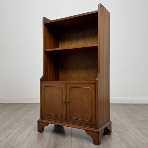 fig 7. A mahogany open bookcase featuring two upper shelves with shaped side galleries above a two-door lower cupboard on bracket feet.