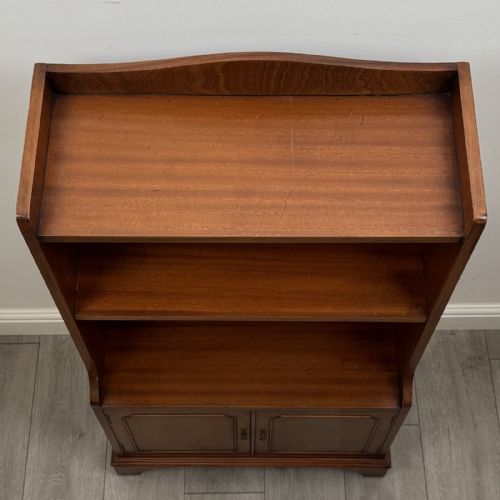 fig 8. A mahogany open bookcase featuring two upper shelves with shaped side galleries above a two-door lower cupboard on bracket feet.