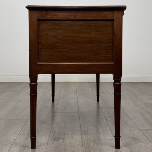 fig 2. An Edwardian mahogany writing table featuring four drawers with brass ring handles, boxwood stringing inlay, a central kneehole aperture, and four slender turned legs.