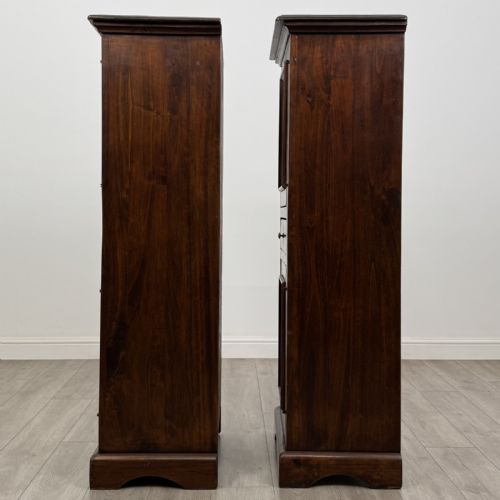 fig 3. A pair of tall dark brown hardwood cupboards featuring a central drawer and panelled doors, with one lower panel decorated with a painted urn motif.