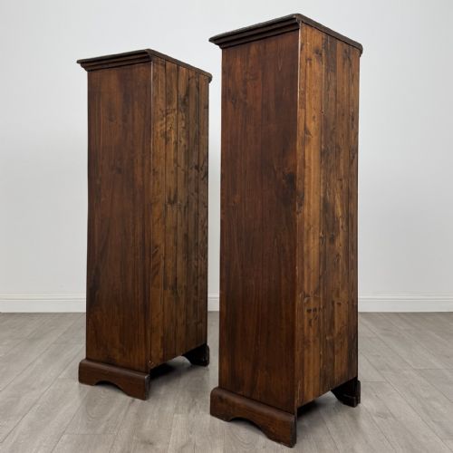 fig 4. A pair of tall dark brown hardwood cupboards featuring a central drawer and panelled doors, with one lower panel decorated with a painted urn motif.