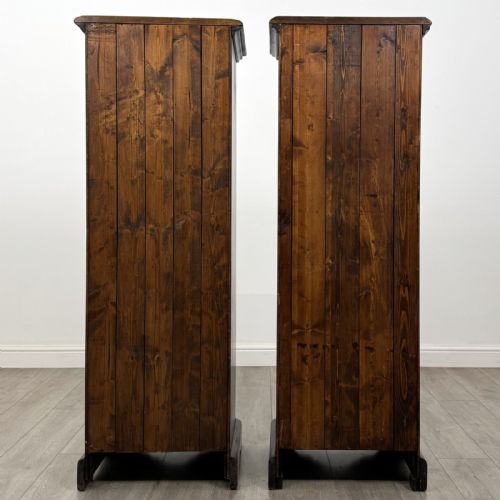 fig 5. A pair of tall dark brown hardwood cupboards featuring a central drawer and panelled doors, with one lower panel decorated with a painted urn motif.