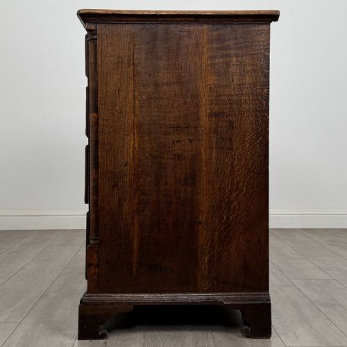 fig 2. An eighteenth-century Georgian oak chest of drawers featuring two short drawers over three long drawers with brass swan-neck handles and bracket feet.