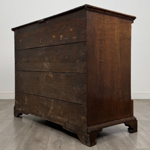 fig 5. An eighteenth-century Georgian oak chest of drawers featuring two short drawers over three long drawers with brass swan-neck handles and bracket feet.