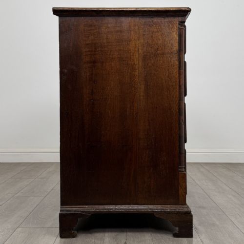 fig 6. An eighteenth-century Georgian oak chest of drawers featuring two short drawers over three long drawers with brass swan-neck handles and bracket feet.