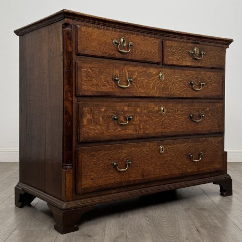 fig 7. An eighteenth-century Georgian oak chest of drawers featuring two short drawers over three long drawers with brass swan-neck handles and bracket feet.