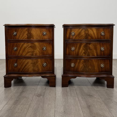 fig 1. A matching pair of Georgian style mahogany bedside chests with serpentine fronts, three drawers each, brass ring handles, and bracket feet.