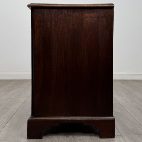 fig 2. An 18th-century dark mahogany low cupboard featuring twin panelled doors with brass keyhole escutcheons resting on bracket feet.