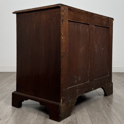 fig 3. An 18th-century dark mahogany low cupboard featuring twin panelled doors with brass keyhole escutcheons resting on bracket feet.