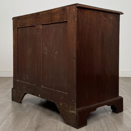 fig 5. An 18th-century dark mahogany low cupboard featuring twin panelled doors with brass keyhole escutcheons resting on bracket feet.