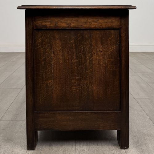 fig 2. A dark oak Jacobean style blanket box featuring a carved lunette frieze across the top rail and three panelled sections with geometric lozenge and rosette motifs.