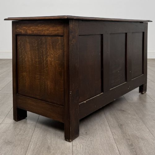 fig 3. A dark oak Jacobean style blanket box featuring a carved lunette frieze across the top rail and three panelled sections with geometric lozenge and rosette motifs.
