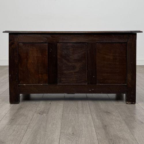 fig 4. A dark oak Jacobean style blanket box featuring a carved lunette frieze across the top rail and three panelled sections with geometric lozenge and rosette motifs.