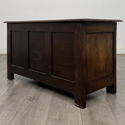 fig 5. A dark oak Jacobean style blanket box featuring a carved lunette frieze across the top rail and three panelled sections with geometric lozenge and rosette motifs.