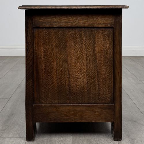 fig 6. A dark oak Jacobean style blanket box featuring a carved lunette frieze across the top rail and three panelled sections with geometric lozenge and rosette motifs.