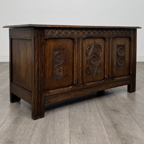 fig 7. A dark oak Jacobean style blanket box featuring a carved lunette frieze across the top rail and three panelled sections with geometric lozenge and rosette motifs.